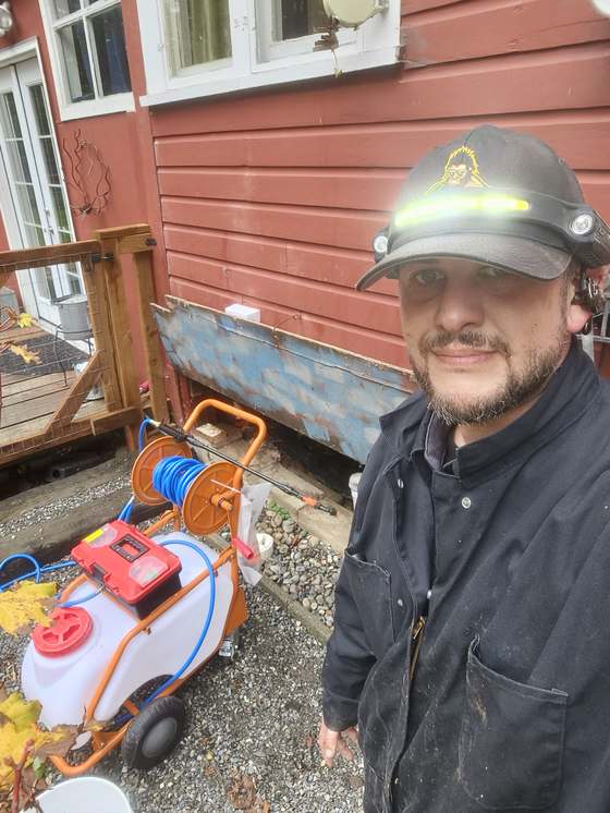 A technician standing with treatment equipment at a home