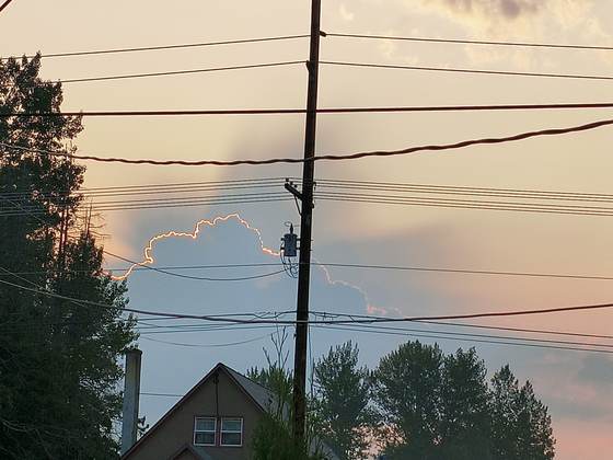 A colorful sunset sky over a home and power lines