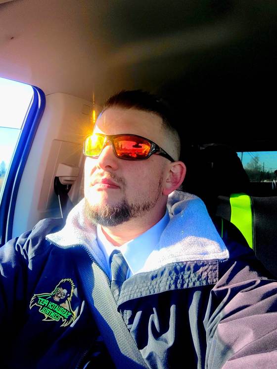 A technician wearing orange sunglasses, seated in a service vehicle