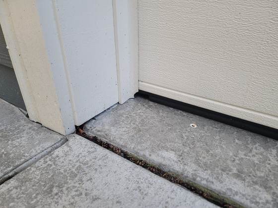 A gap where a door threshold meets a concrete slab