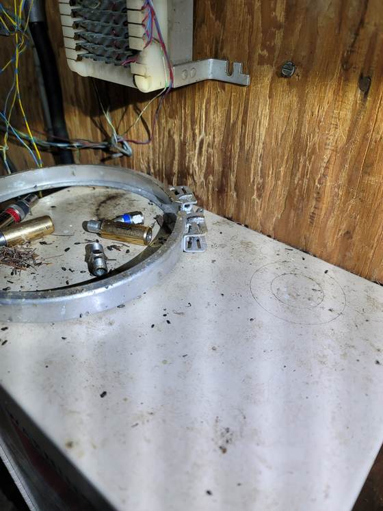 Mouse droppings scattered over the top of an appliance in a utility room, among loose fittings and a metal ring