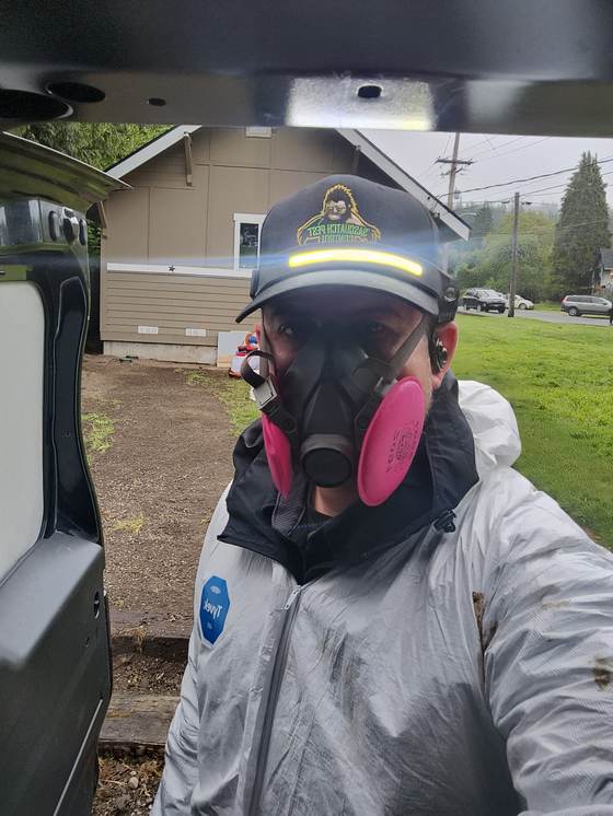 Kristofer Elling at the open back of the van in a white protective suit, half-face respirator and a headlamp on his cap
