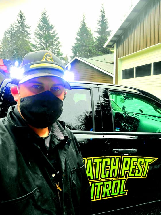 Kristofer Elling in a cap with twin headlamps and a face mask beside the wrapped truck, lights on and ready for an inspection