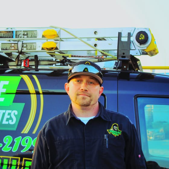 Travis (TJ) Hansen in a branded cap and safety glasses, standing by the wrapped van