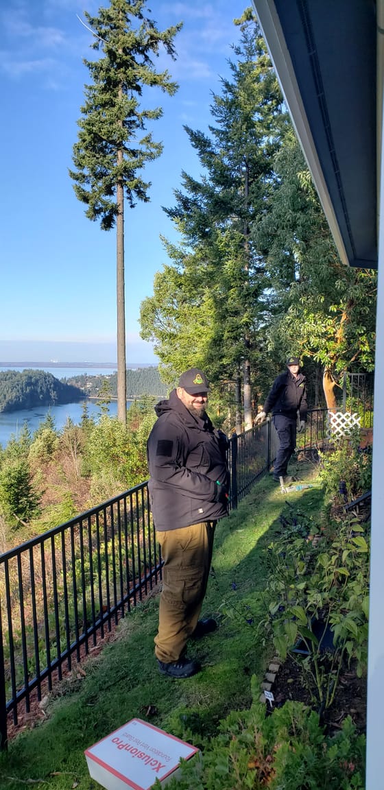 Tyson Elling and a technician working a hillside garden above the water, islands and forest behind them
